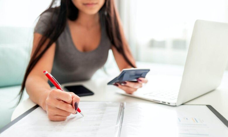 Asian woman using calculator and laptop for calaulating home budget finance taxes