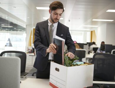 Fired male employee packing box of belongings in an office