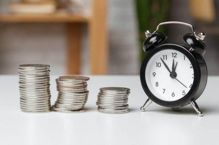 Alarm clock and money coins on the table.