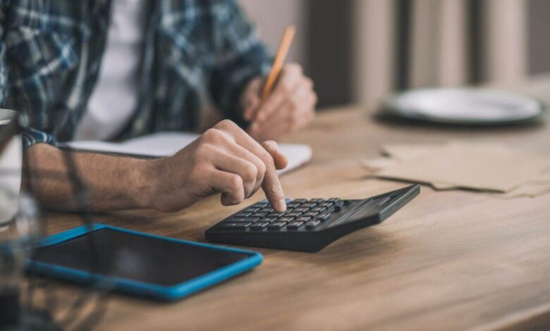 Man using a calc and other gadgets for financial estimation