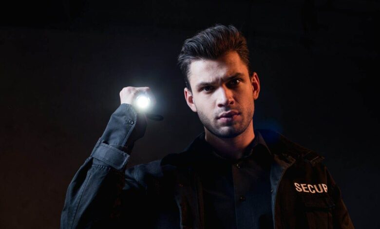 guard in uniform holding flashlight and looking at camera