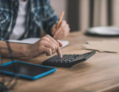 Man using a calc and other gadgets for financial estimation