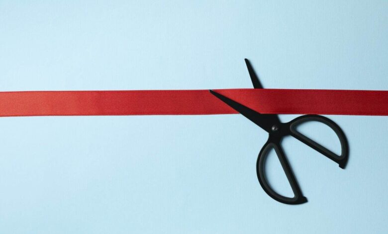 Black scissors and red ribbon on blue background