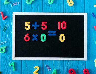 top view of blackboard with math sums, colorful numbers and paper clips on blue wooden background