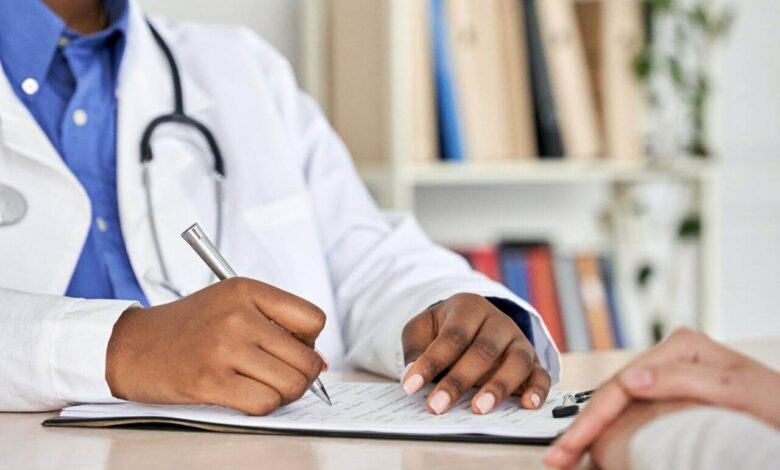 African black doctor consult woman patient filling medical form at appointment.