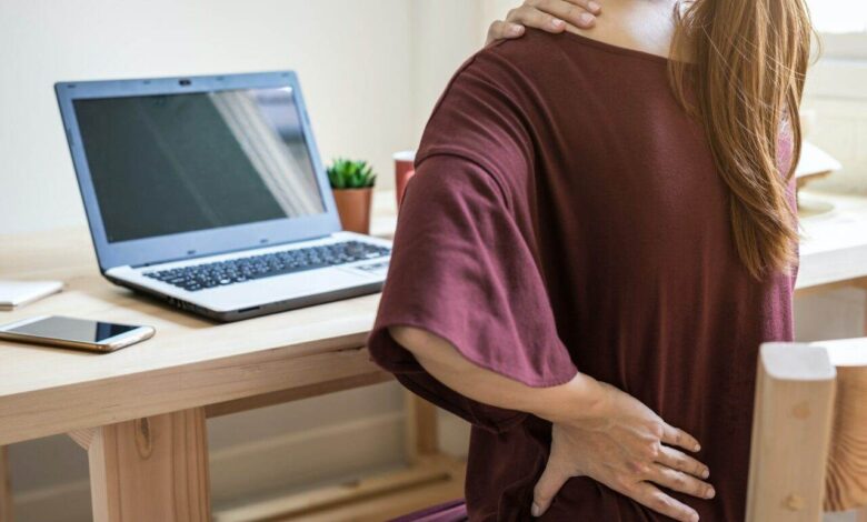 Young woman working at home and having back pain