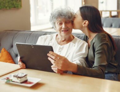 Girl teaching her grandmother how to use a tablet