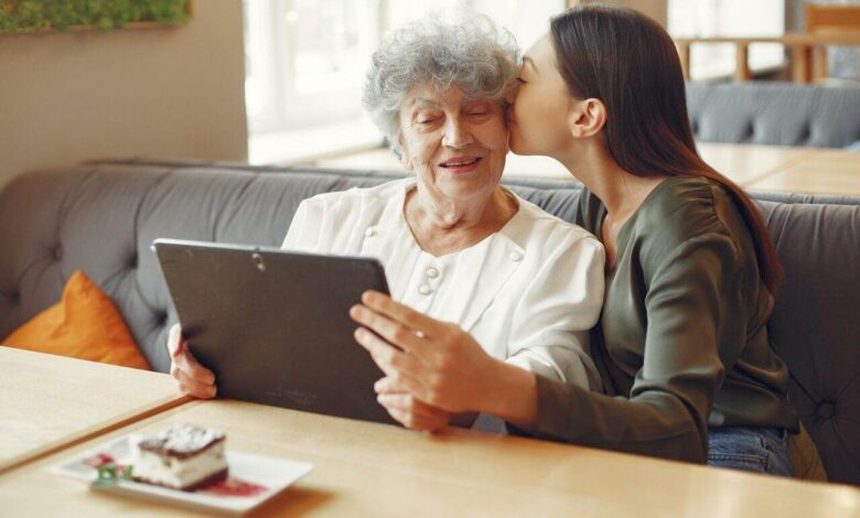 Girl teaching her grandmother how to use a tablet