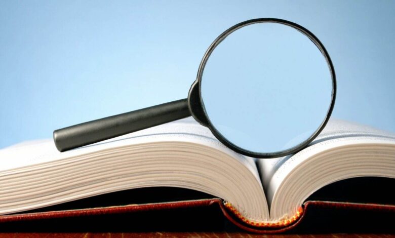 book and a magnifying glass on a blue background